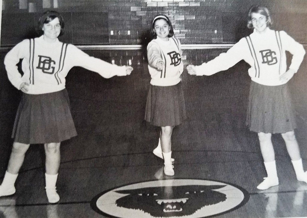 From 1966 Yearbook, Sophomore year.  
Junior Varsity Cheerleaders (L-R) Amy Gamble, Becky Ricketts, Carol Simon.
Game of chance...whose fist holds the quarter?